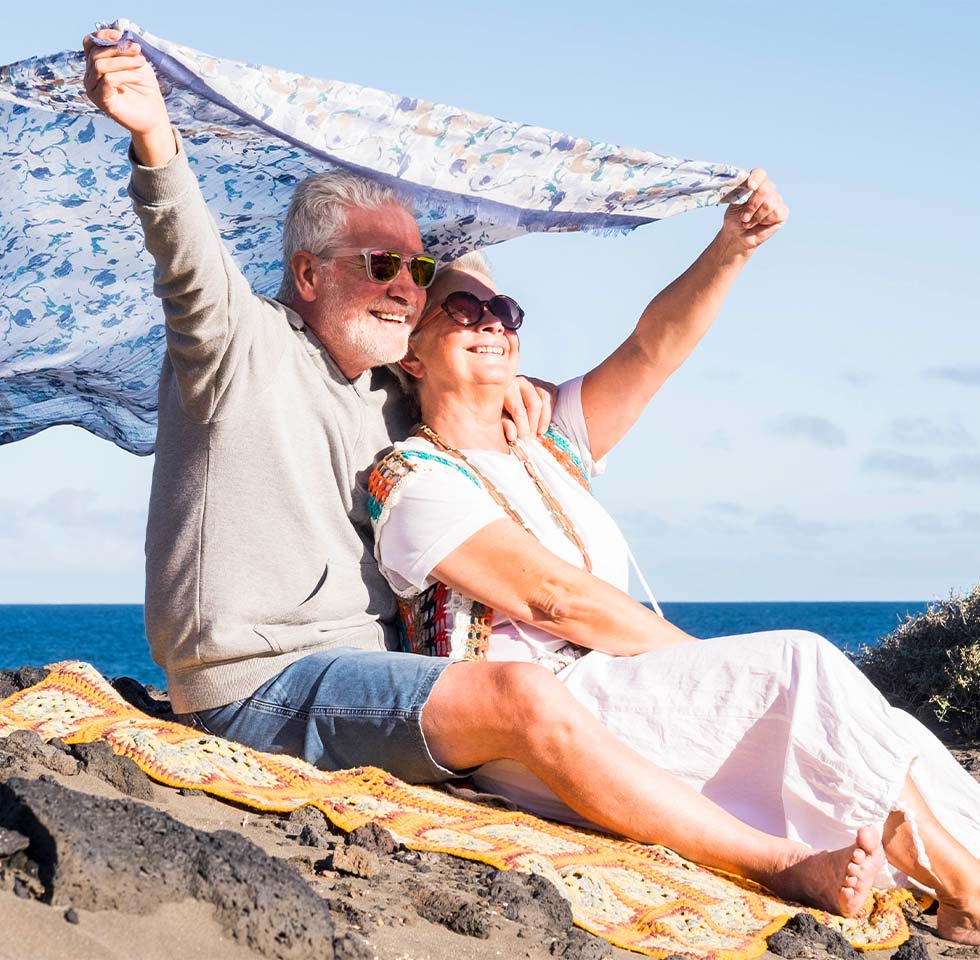 happy senior couple on beach holding blanket in the wind what is an annuity bakersfield ca